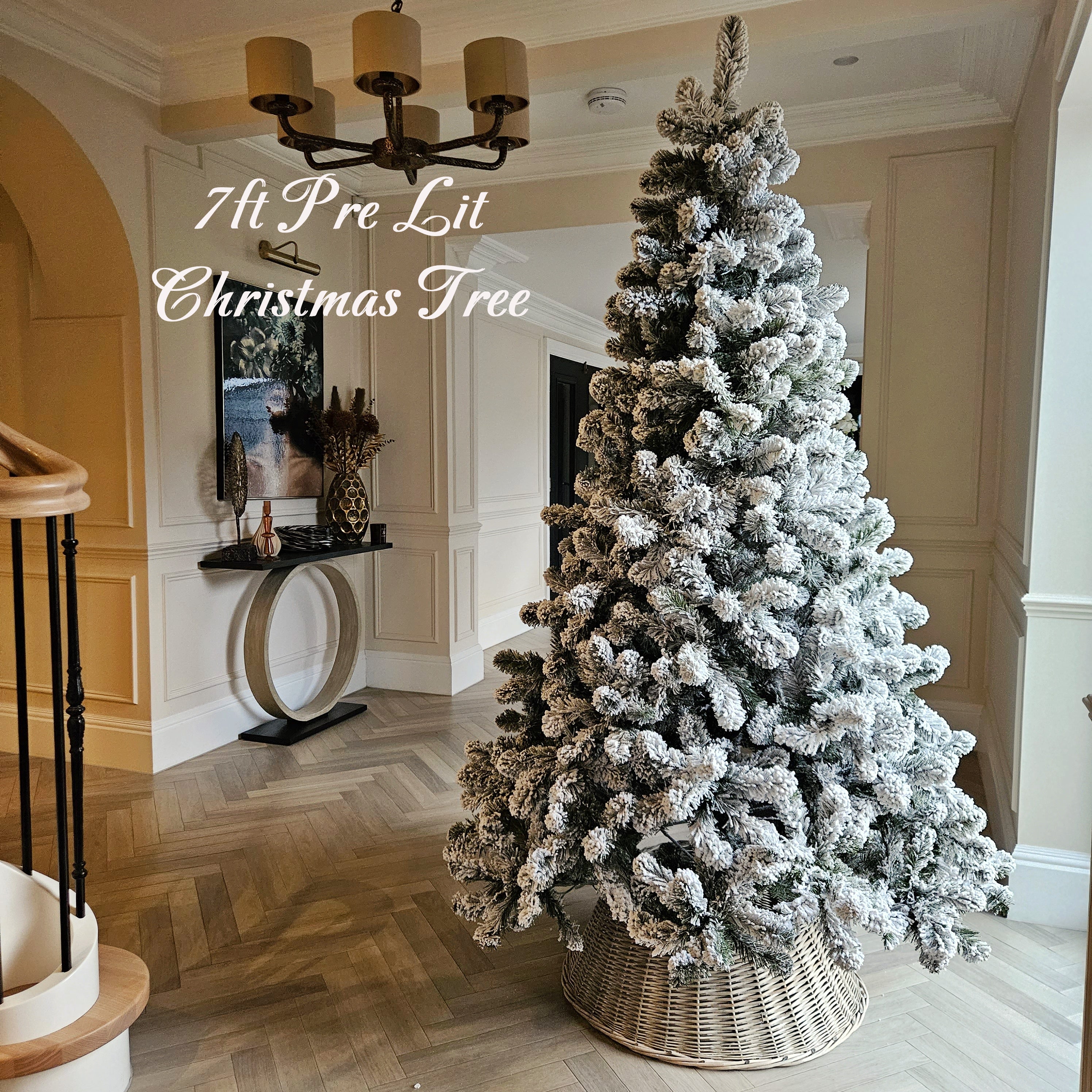 7ft pre lit Christmas tree – snow flocked with wicker tree skirt displayed in a hallway

